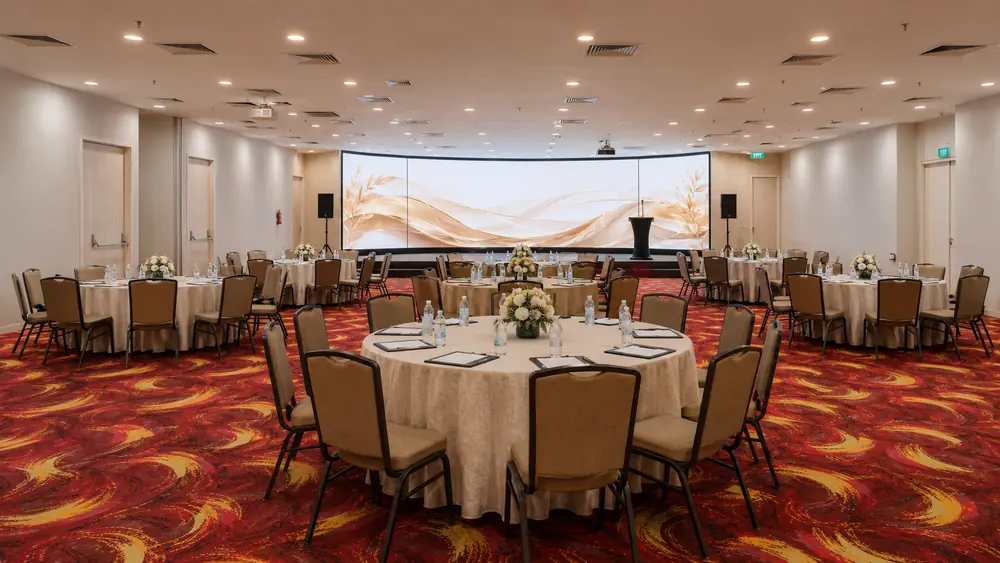 Round tables and greenery set across the full pillarless hall